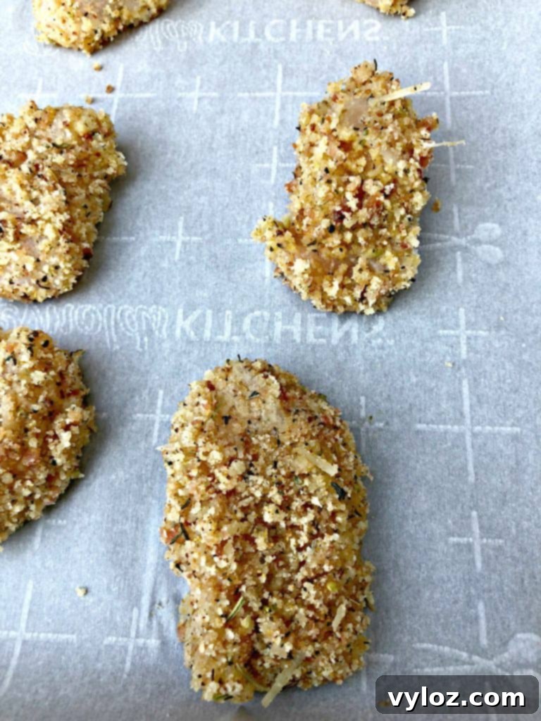 More raw breaded chicken pieces on a tray