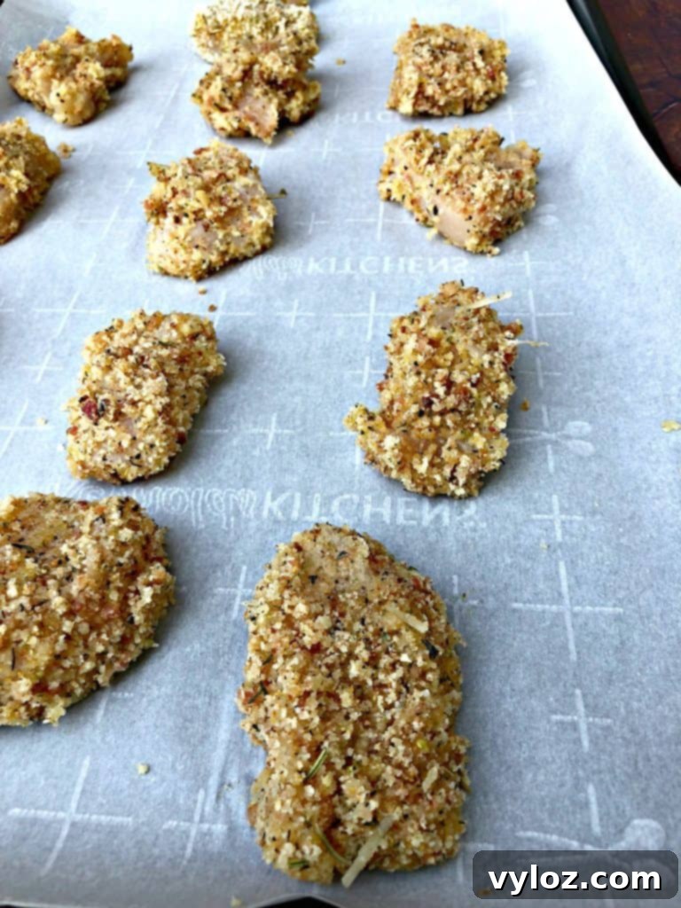 Several raw breaded chicken pieces organized on a tray