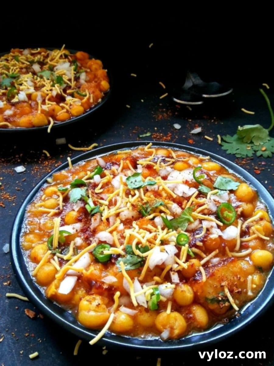 Two plates of Matar Chaat, a delicious Indian street food snack made with white peas, garnished with fresh onions, green chilies, tamarind water, and coriander leaves.