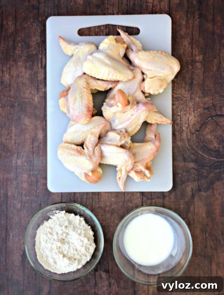 Crispy Air Fryer Buttermilk Fried Chicken 3 raw chicken wings on a cutting board with buttermilk and flour