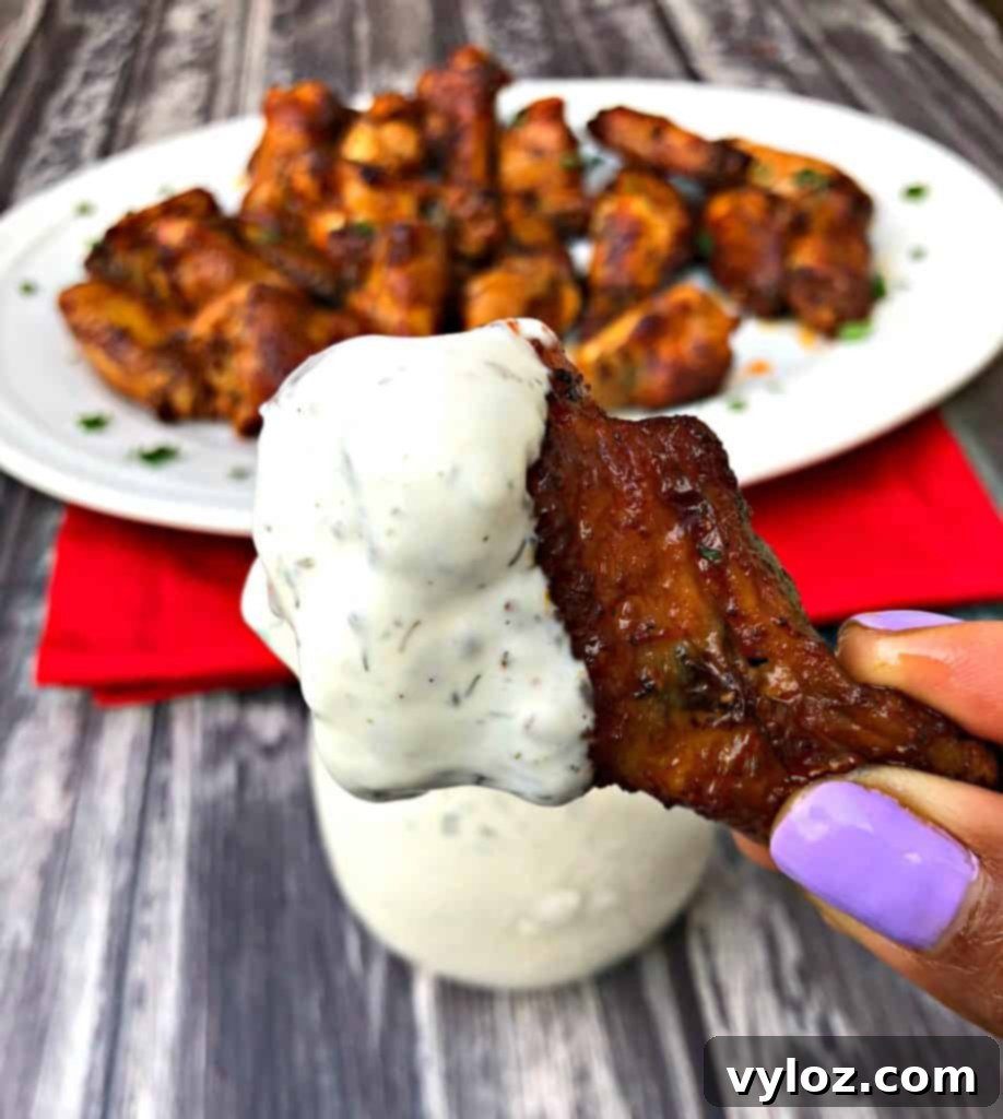 Ultimate Air Fryer Buffalo Wings 11 Person holding an air fryer buffalo chicken wing with ranch dressing