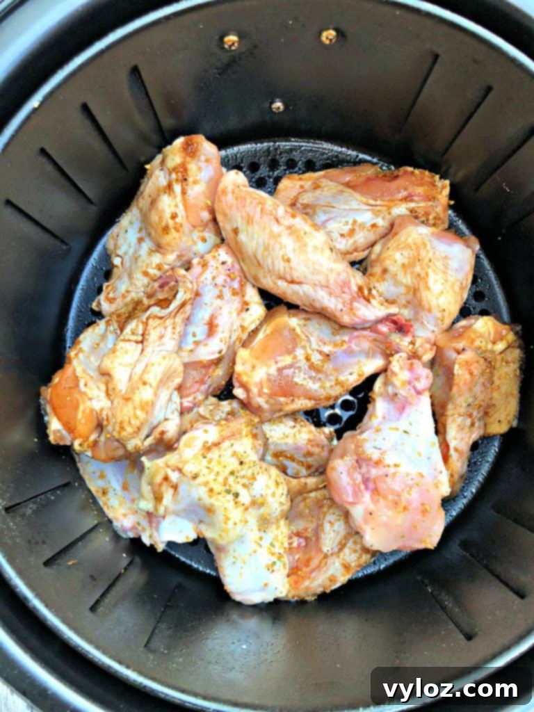 Ultimate Air Fryer Buffalo Wings 4 Raw seasoned chicken wings arranged in an air fryer basket