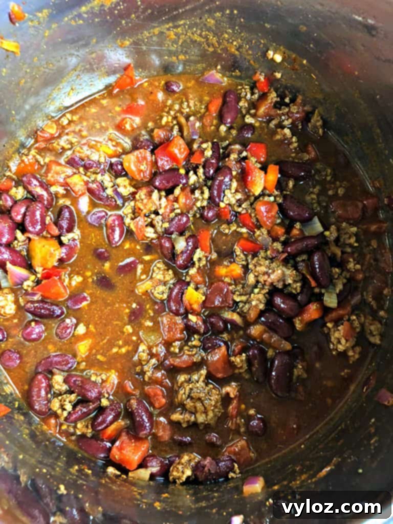 A top-down view of Instant Pot beef chili in a rustic bowl, garnished with cilantro and a dollop of sour cream.