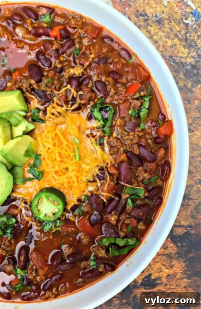 A bowl of Instant Pot beef chili generously topped with shredded cheddar cheese, ready for serving.