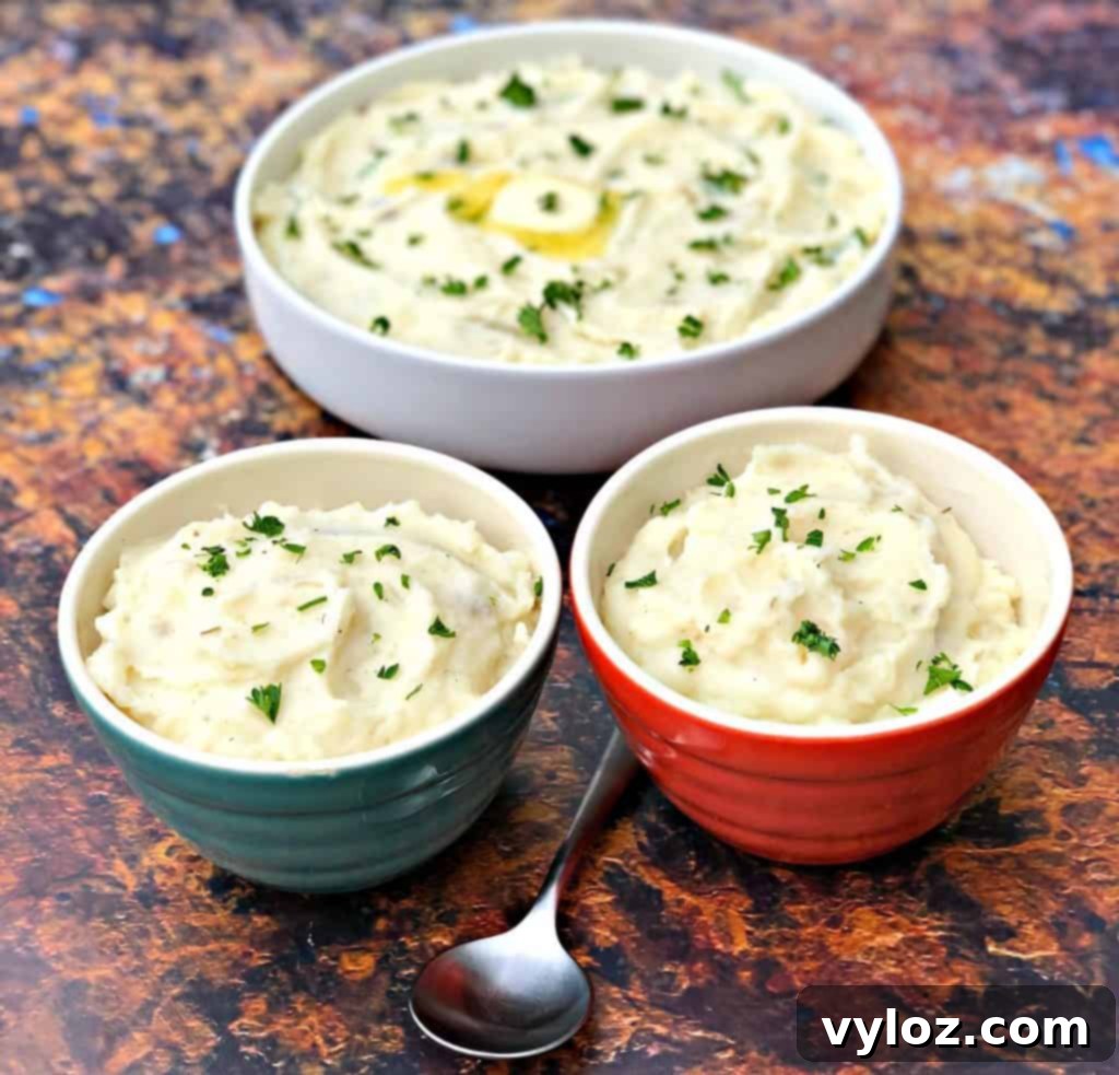 Three artfully arranged bowls of Instant Pot garlic mashed potatoes, garnished with fresh chives, ready to be served.