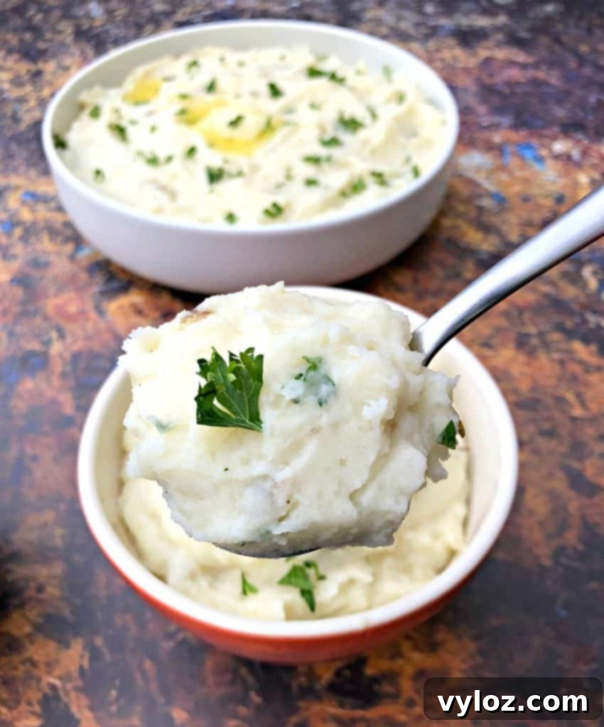 A large serving spoon full of Instant Pot garlic mashed potatoes, held above three bowls filled with the same delicious dish.
