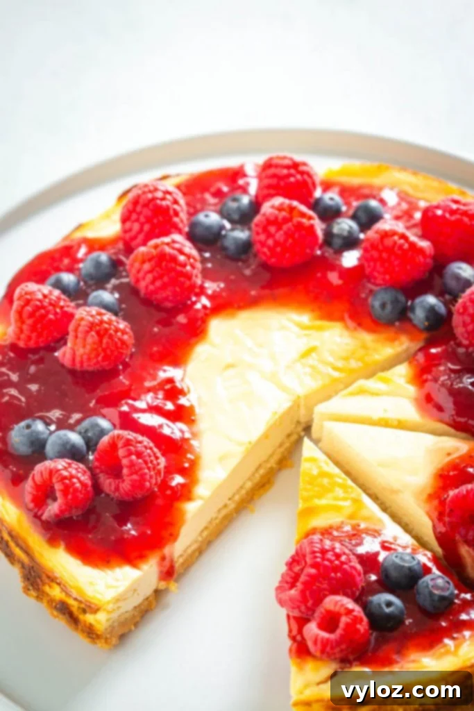 A slice of delicious sugar-free cheesecake on a white plate, topped with fresh mixed berries and a delicate drizzle, highlighting its creamy texture and golden almond flour crust.