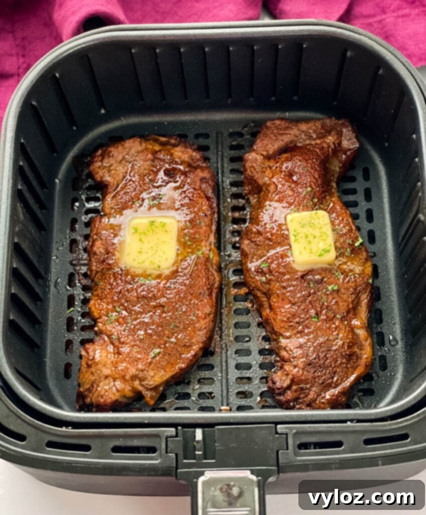 Perfectly cooked, juicy air fryer steaks topped with melting butter and fresh herbs.