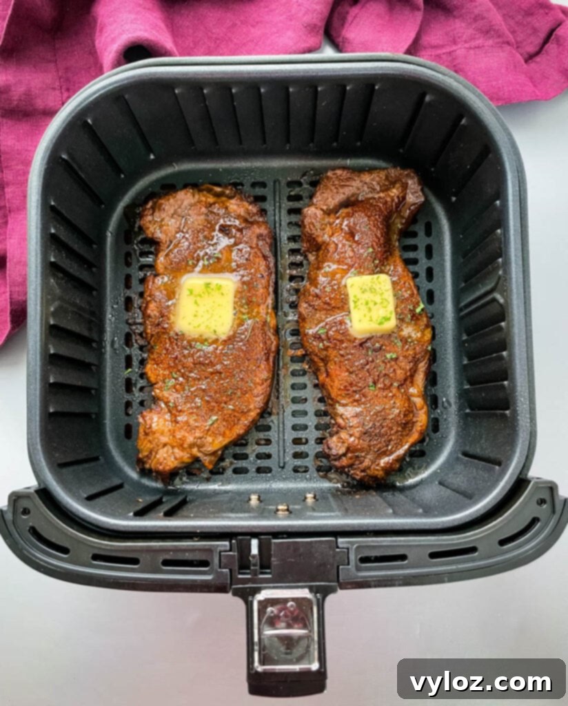 Cooked air fryer steaks, glistening with melted butter, ready to be sliced.