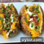 Crispy Air Fryer Baked Potatoes 7 Air fryer loaded baked potato on a white plate