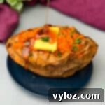 air fryer sweet potato with butter drizzled with honey on a blue plate